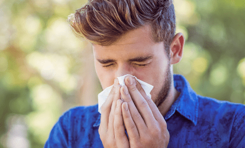 Man sneezing outdoors