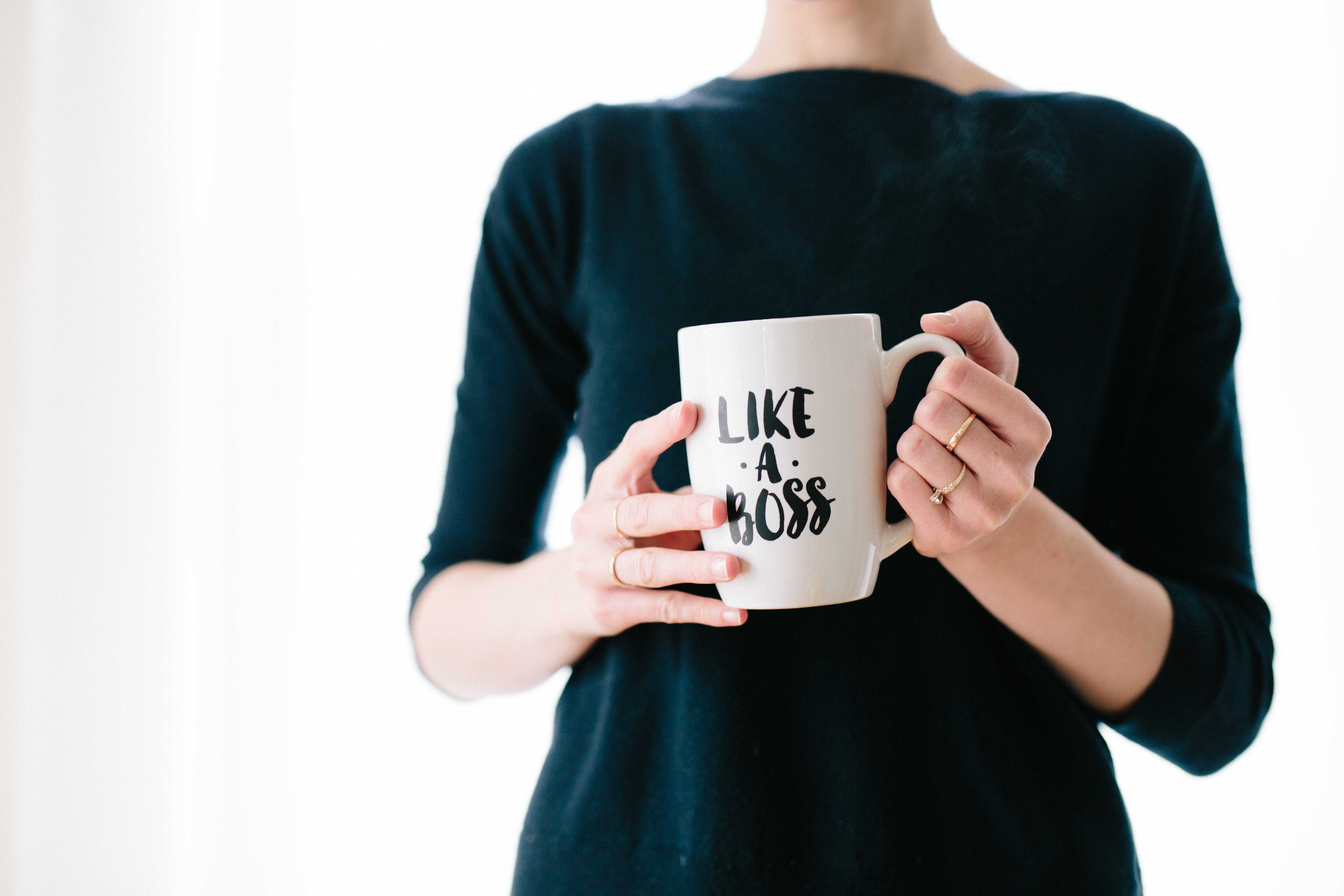 a person holding a coffee mug that reads, "like a boss"