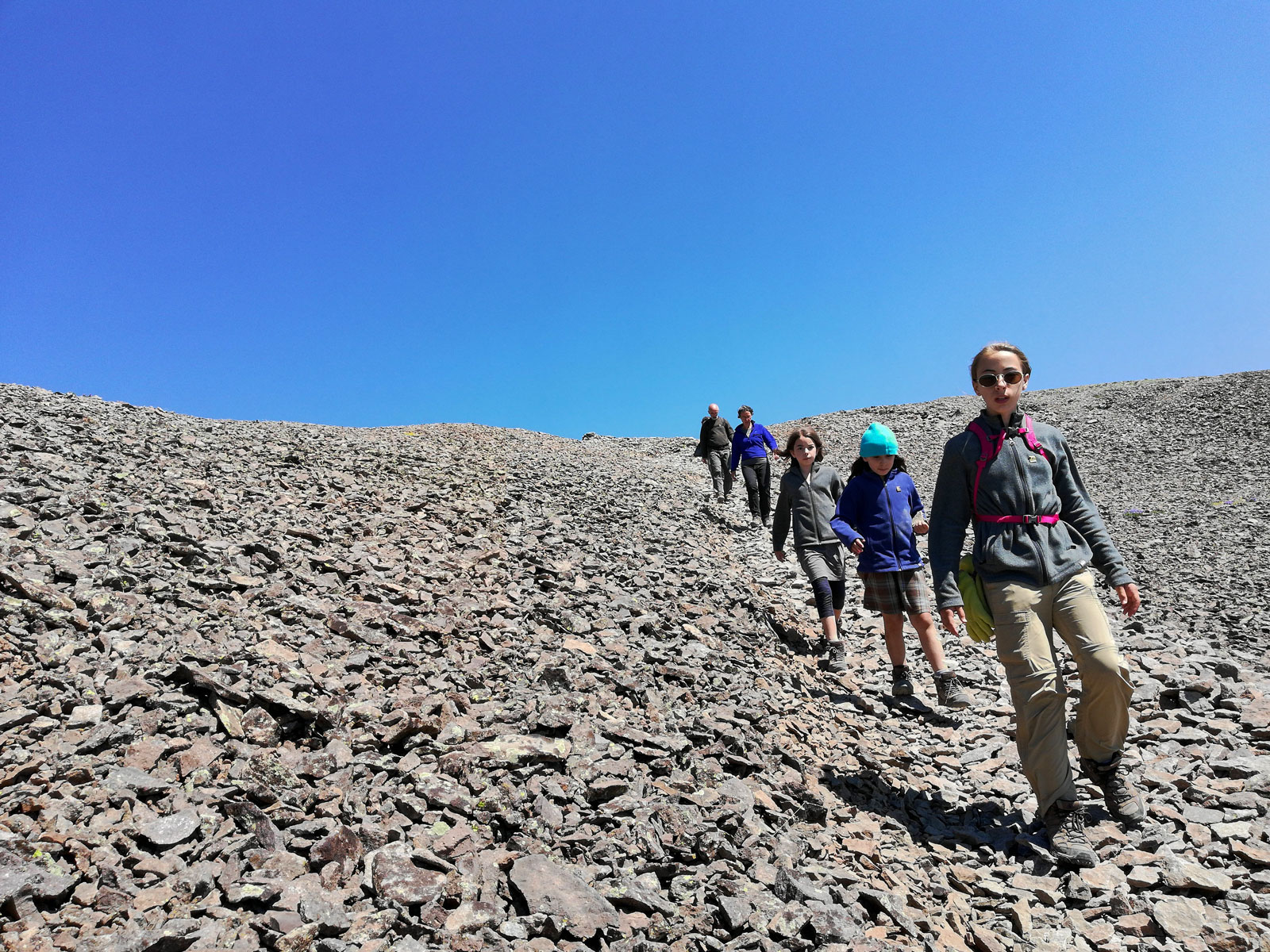 Hikers walking down a scree covered mountainside descending Avalanche Peak in Yellowstone National Park