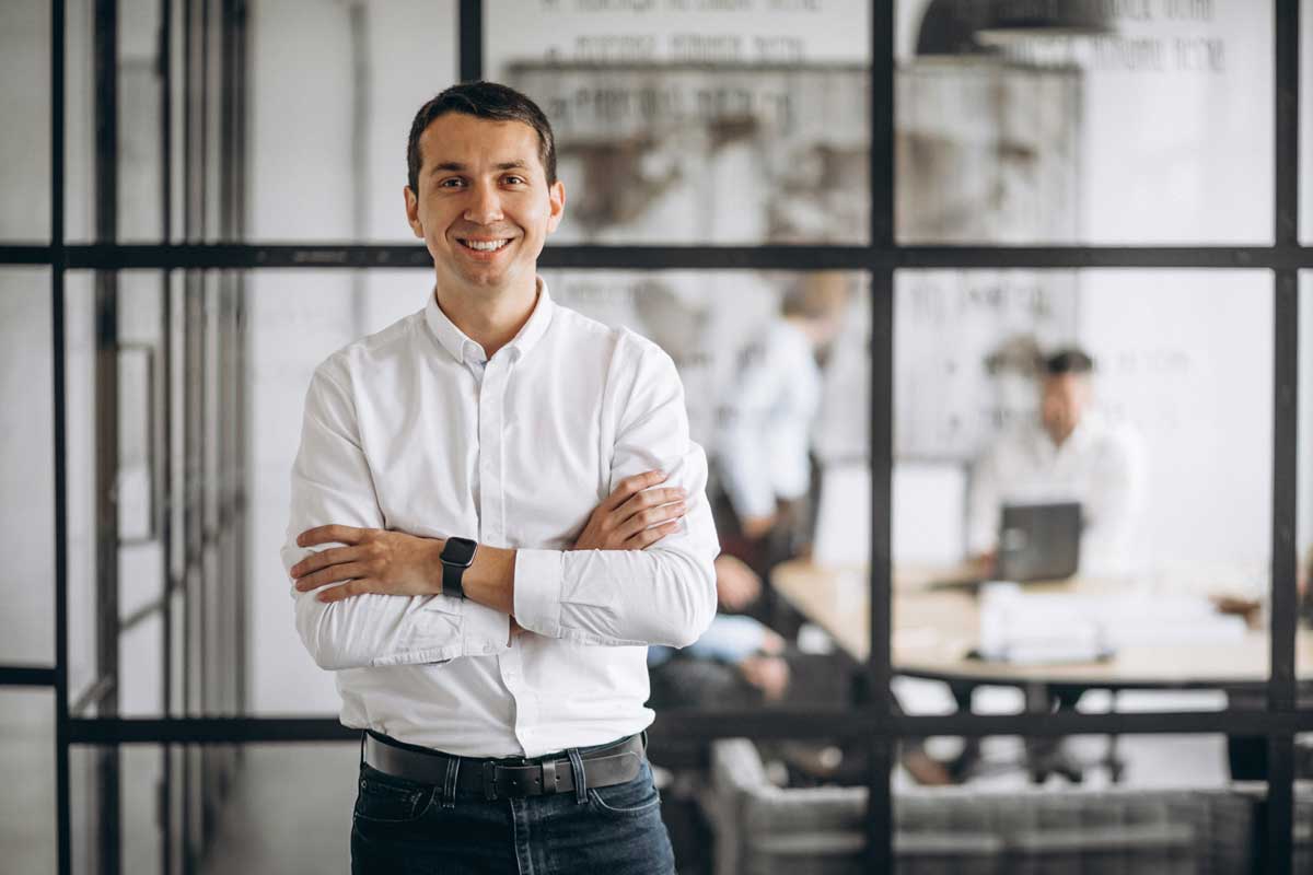 Man smiling at the camera whilst standing in a modern office