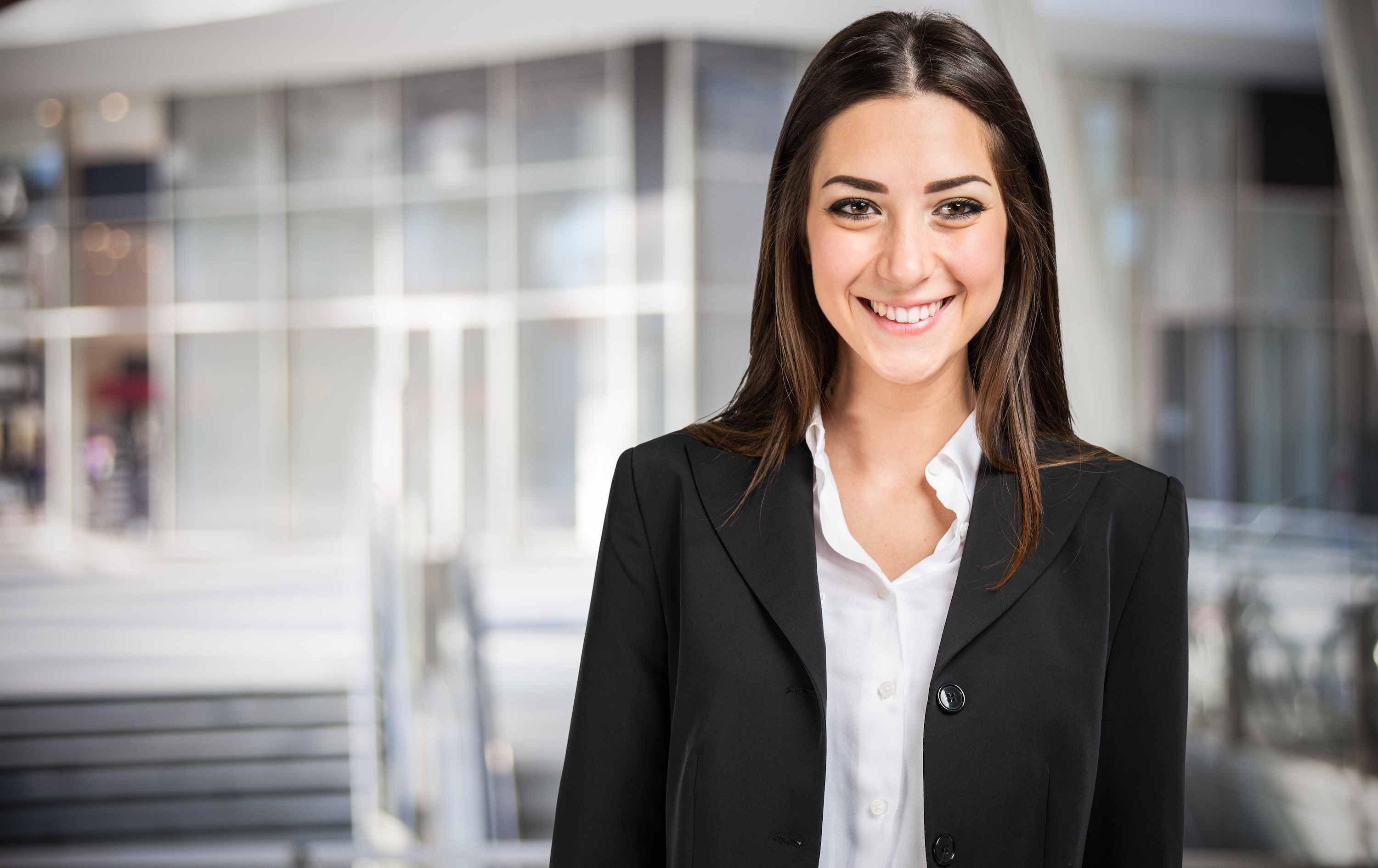 Young business woman in office environment looking at camera in black suit