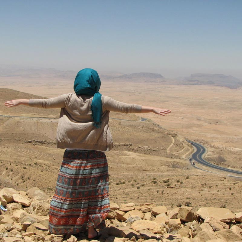 Go on your trip - Woman with headwrap looking down off a mountain