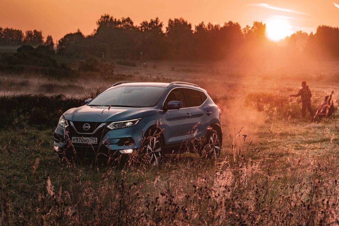 Carro SUV da Nissan andando no campo ao pôr do sol