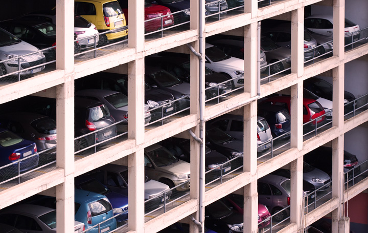 Prédio de estacionamento com vários andares repletos de carros nas vagas