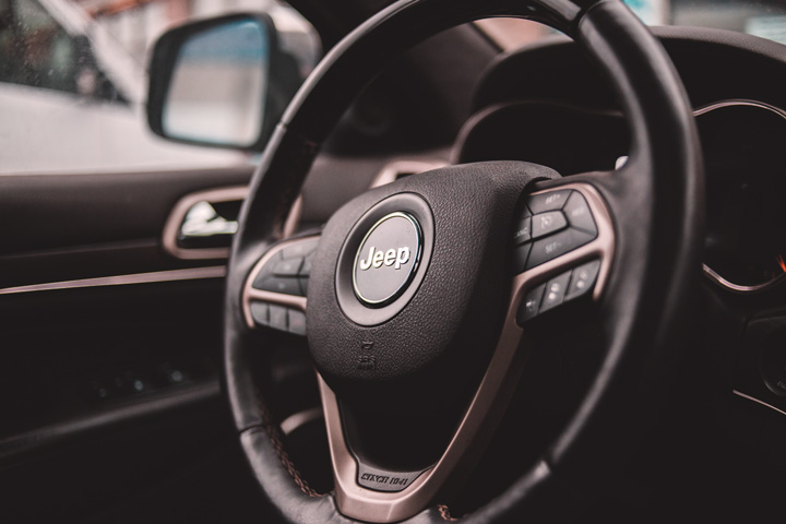 Close em volante de Jeep Renegade destacando símbolo da marca e controles do carro