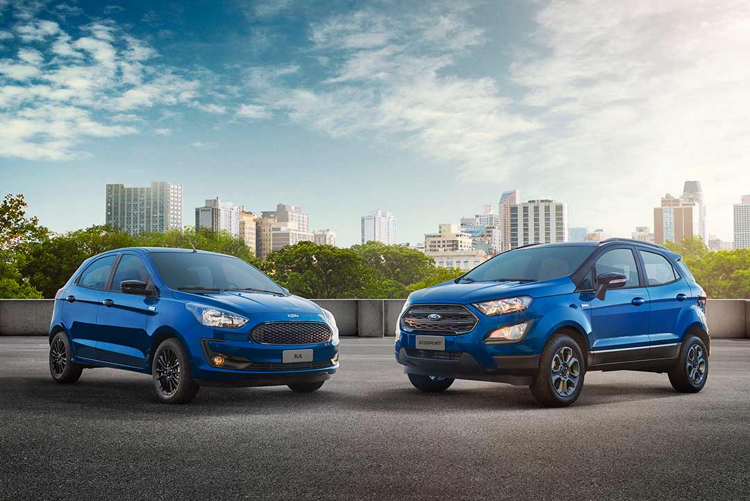 Ford Ka e Ford Ecosport azuis estacionados com prédios da cidade ao fundo