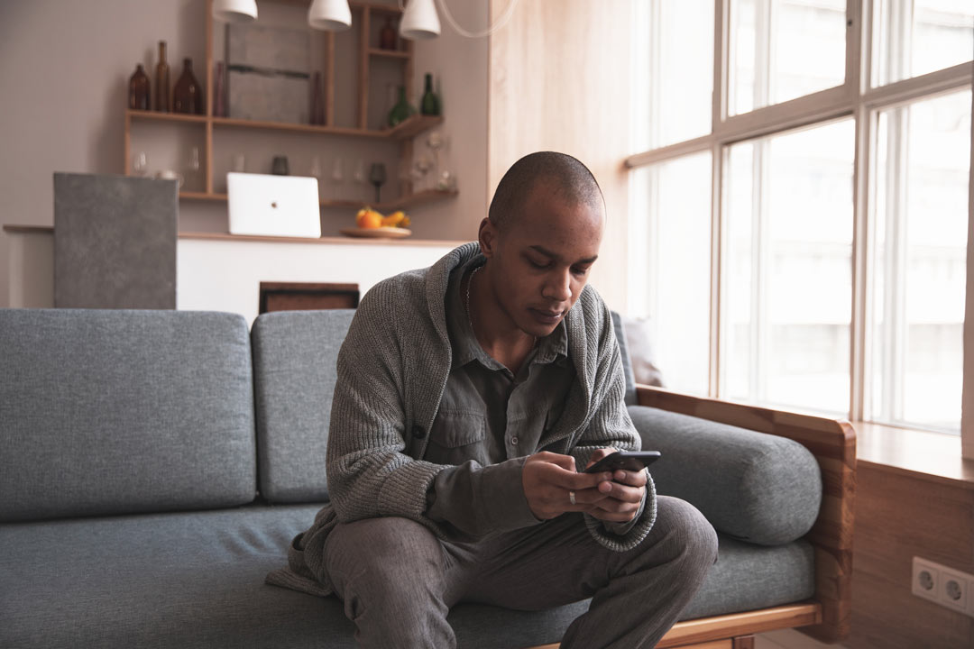 Homem no sofá de sua casa usando aplicativo da CARUPI em seu celular