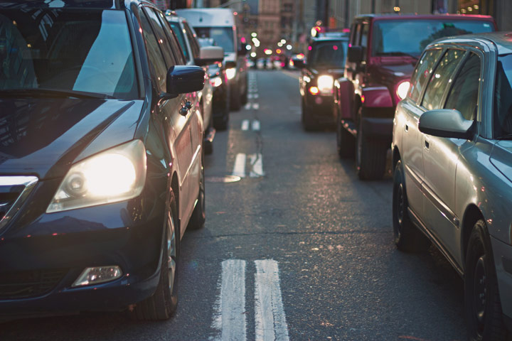 Filas de carros parados em rua congestionada de uma cidade ao anoitecer