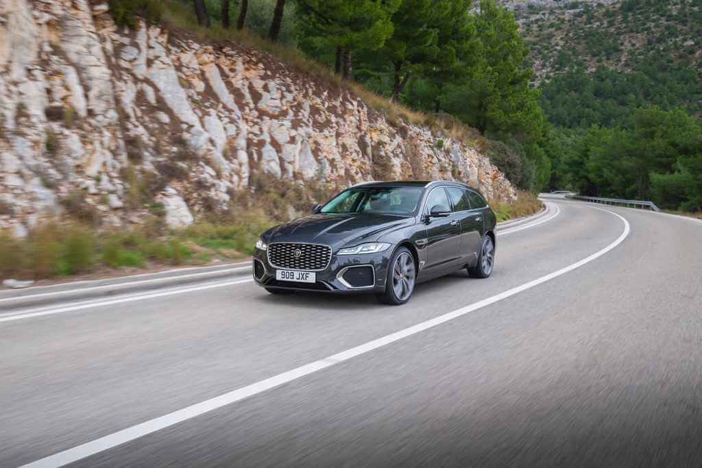 Carro Jaguar XF em rodovia da Europa cercada por pinheiros