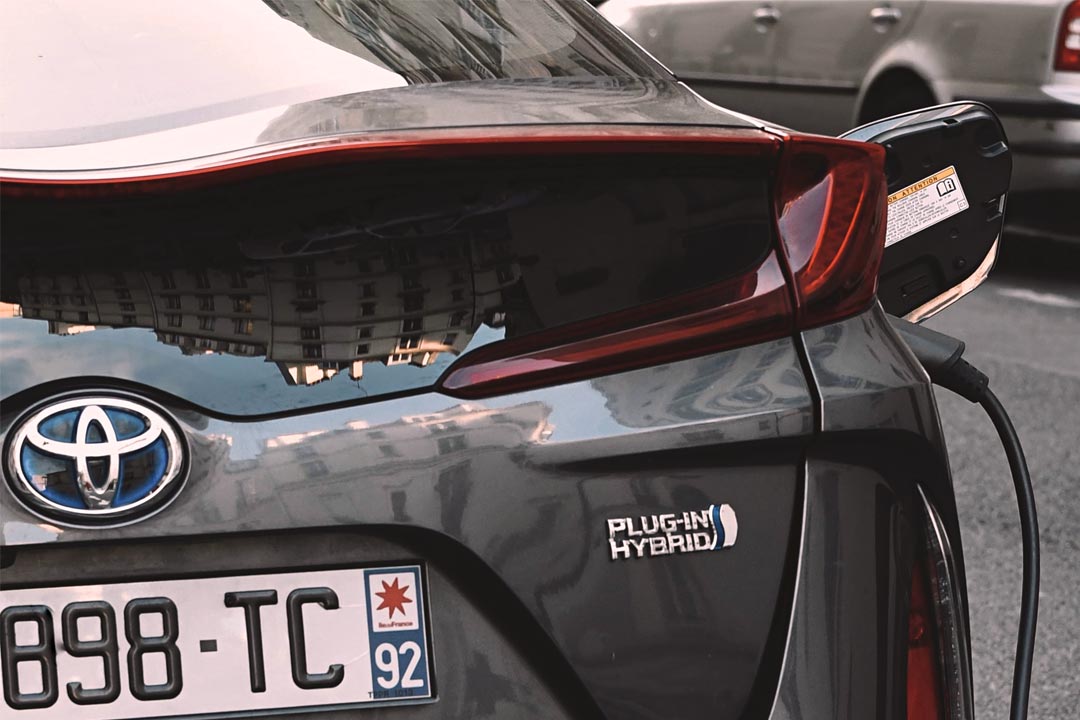 Close em traseira de carro Toyota Prius com cabo de recarga plugado em entrada