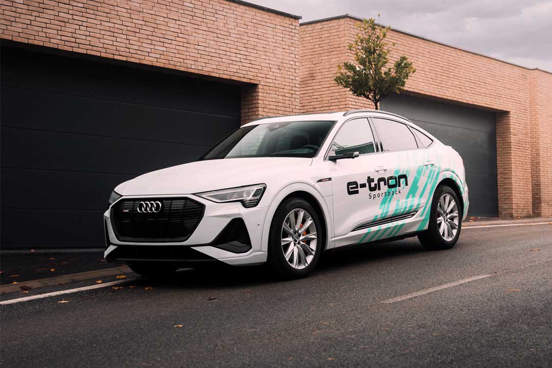 Carro elétrico Audi e-tron estacionado em rua em frente a galpão com portões fechados