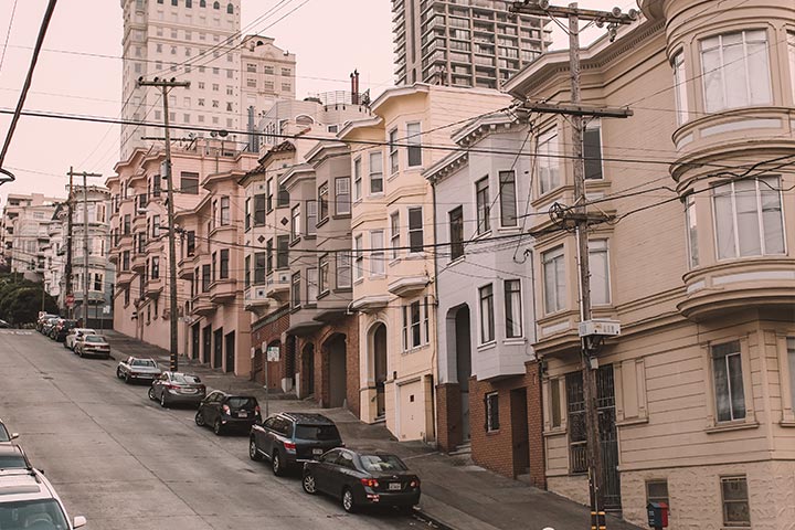 Ladeira na cidade de San Francisco com diversos carros estacionados em frente a casas de estilo vitoriano