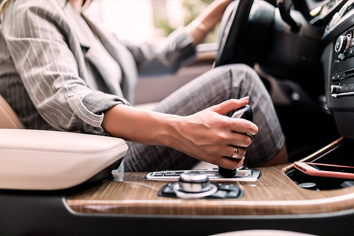 Detalhe de mulher de negócios segurando câmbio automático de carro de luxo enquanto dirige