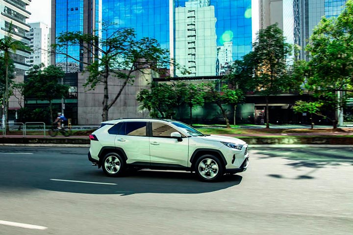 SUV Toyota RAV 4 trafegando por avenida da cidade cercada de prédios espelhados