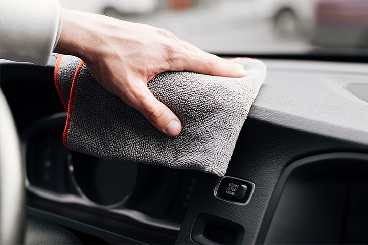 Close de homem limpando painel do carro com uma flanela macia