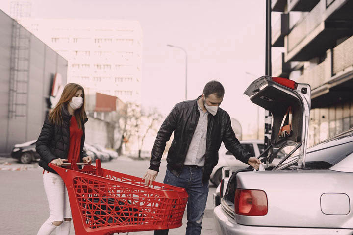 Casal guardando compras de mercado em porta-malas de carro