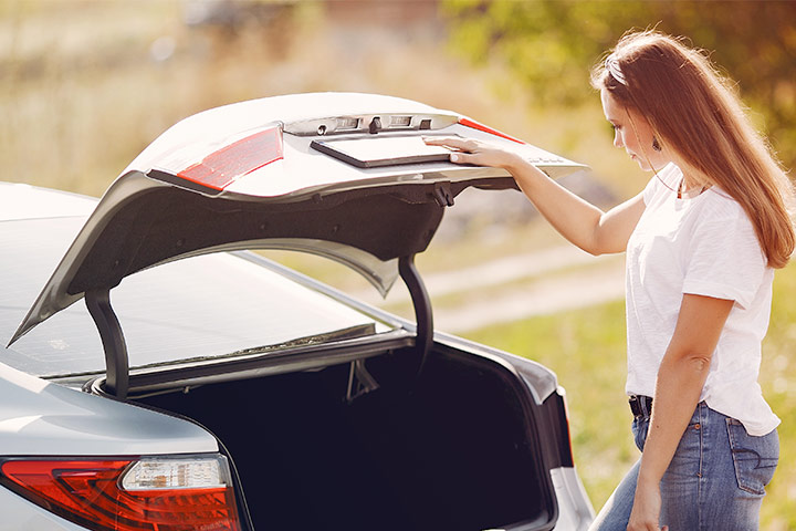Jovem mulher abrindo porta-malas de carro para averiguar seu tamanho interno