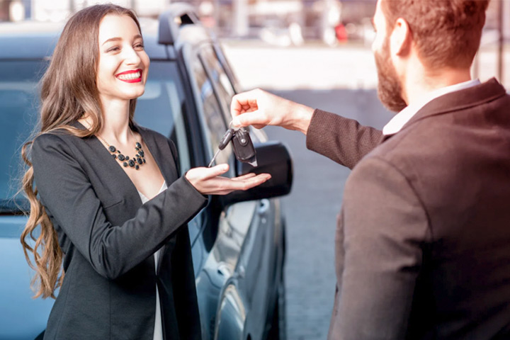Jovem mulher recebendo as chaves do carro usado que acabou de comprar