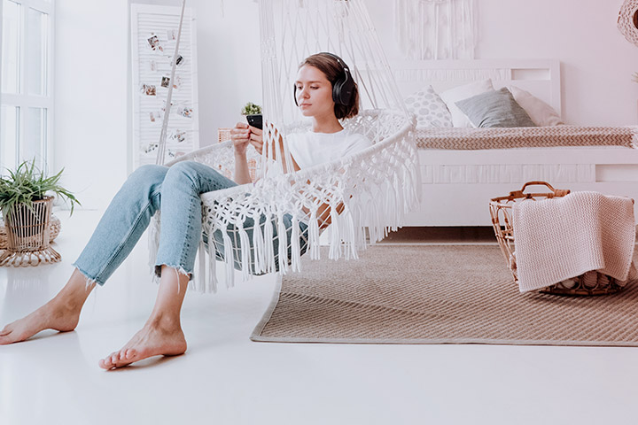 Jovem mulher relaxando na rede em sua sua casa e acessando aplicativo da Carupi para comprar carro online