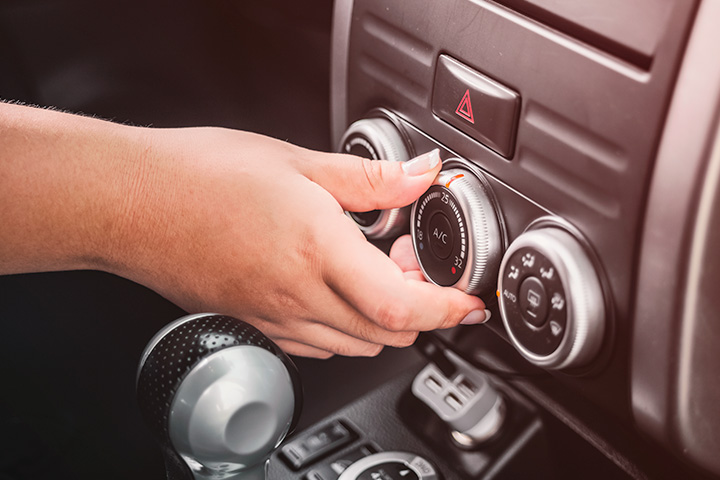 Destaque para mão regulando botão do ar condicionado em painel de instrumentos de carro