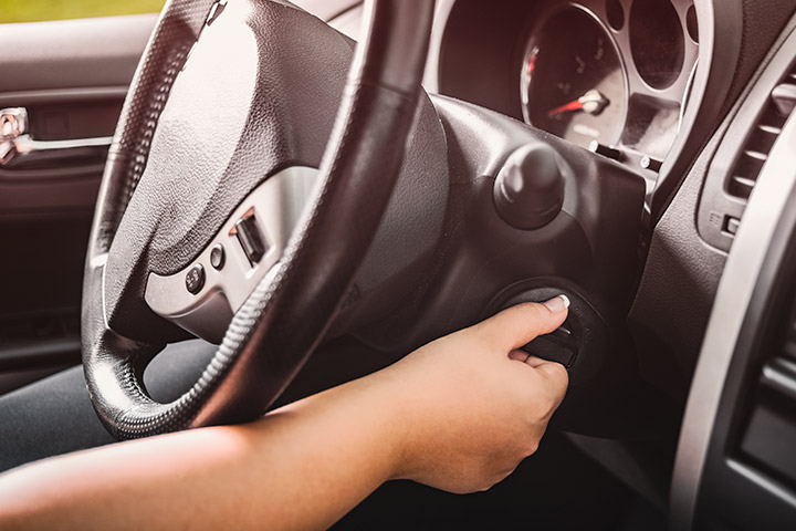 Mão de mulher girando chave de carro para dar partida no veículo que ficou parado por muito tempo