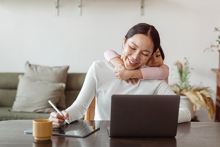 Mãe em casa acessando laptop para comprar carros online na CARUPI abraçada com sua filha