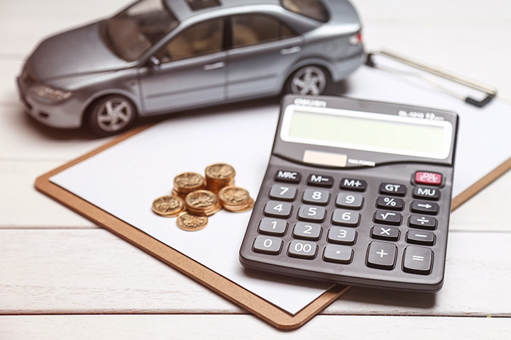 Mesa com prancheta, calculadora, moedas e miniatura de um carro juntos