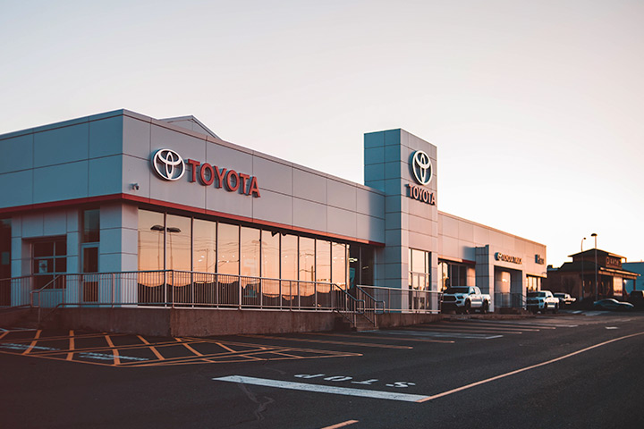 Fachada de concessionária Toyota ao entardecer com por-do-sol refletindo nos vidros