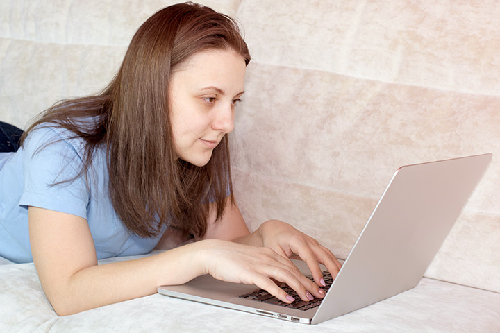 Jovem mulher relaxando em sofá de casa enquanto acessa site da CARUPI em laptop