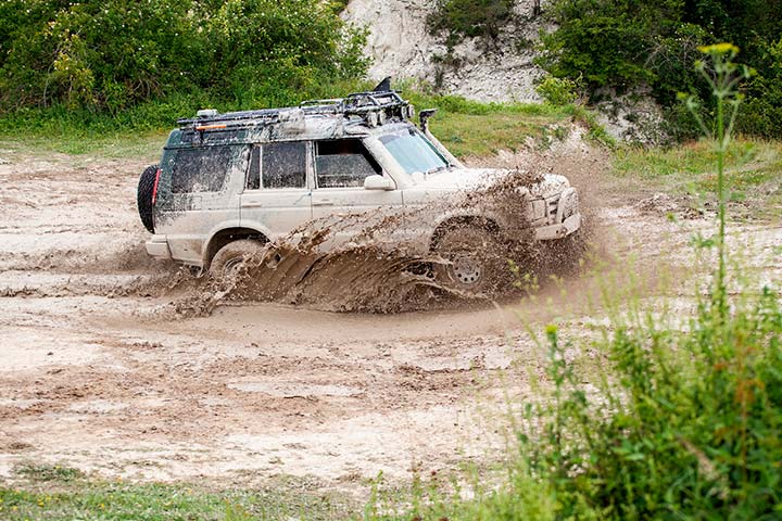 SUV 4x4 usado atravessando poça de lama em ambiente externo