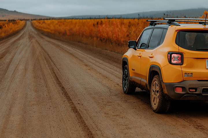 Jeep Renegade 4x4 amarelo em estrada rural com paisagem ao fundo