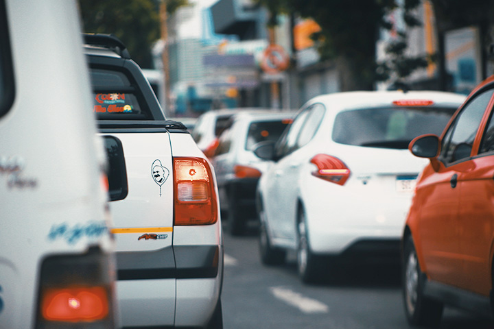 Congestionamento em rua da cidade com diversos carros parados vistos por trás