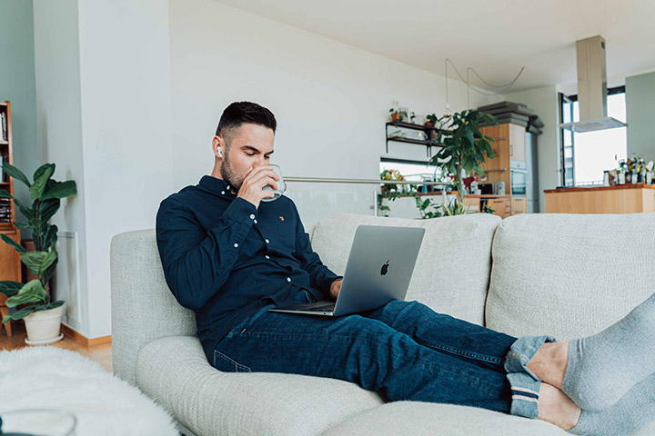 Jovem rapaz relaxando em sofá de sua casa e acessando site da Carupi para comprar e vender carros online