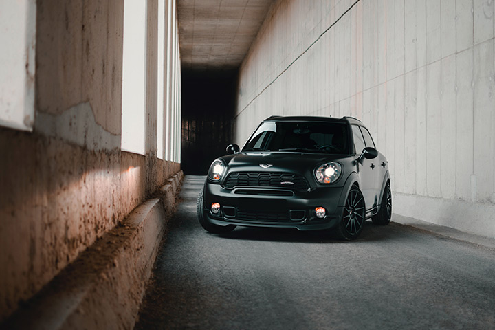 Mini Cooper preto em rua estreita de cenário urbano