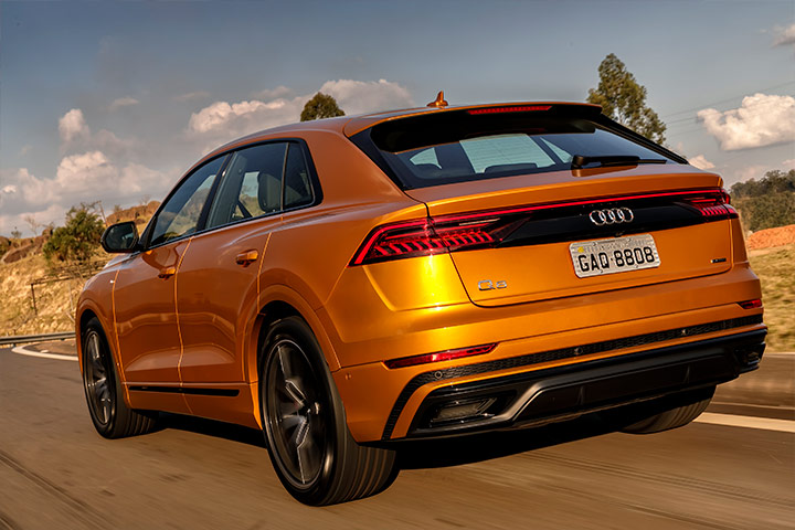 Audi Q8 de cor laranja visto por trás em rodovia com paisagem ao fundo