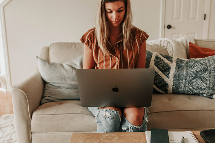 Jovem mulher em sofá de sua casa acessando website Carupi para comprar e vender carros