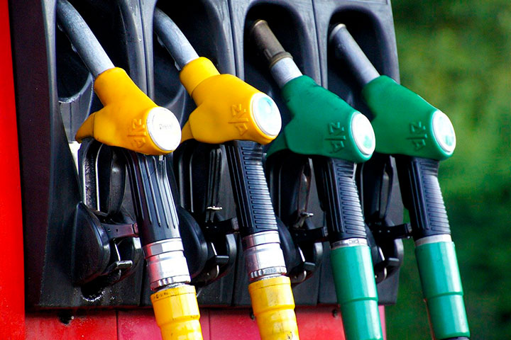 Bomba de combustível em posto de gasolina com destaque para mangueiras em cores amarela e verde