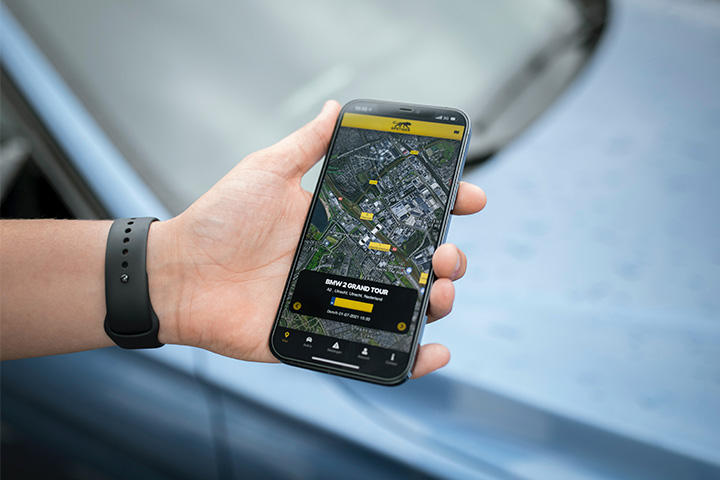 Close em mão de rapaz segurando smartphone com aplicativo de rastreamento veicular aberto mostrando mapa e posição de veículo