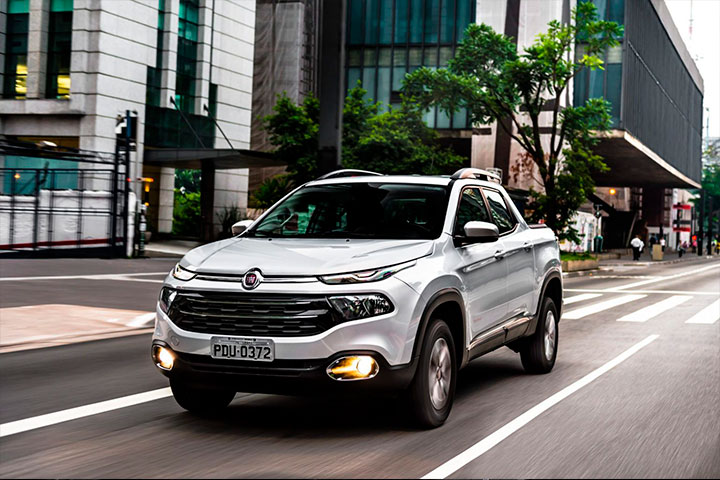 Fiat Toro prateada em rua de grande cidade com prédios ao fundo