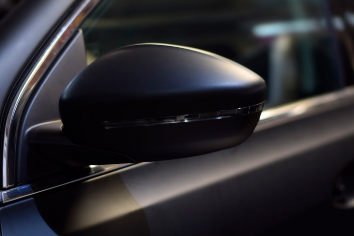 Detalhe de espelho retrovisor de carro com envelopamento automotivo preto fosco