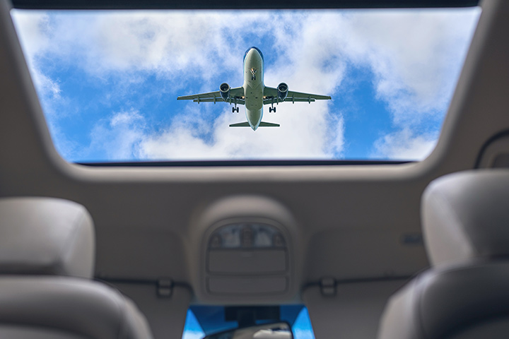 Avião passando por cima de carro e visto de dentro do veículo através do teto solar