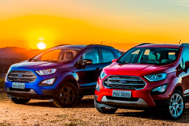 Dois carros Ecosport azul e vermelho parados em estrada de terra com belo entardecer ao fundo