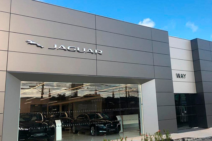 Visão externa de concessionária da Jaguar mostrando fachada e carros em seu interior
