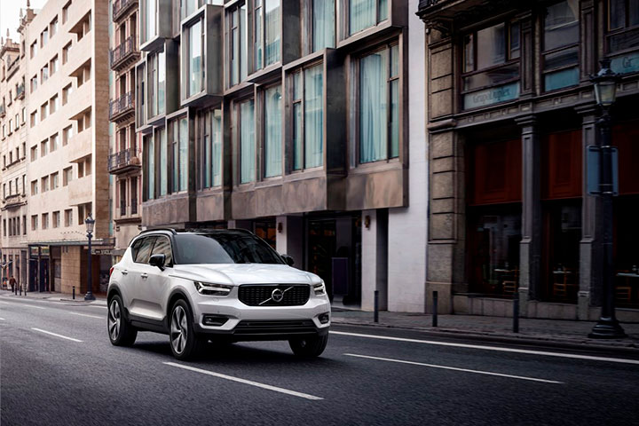 Volvo XC40 branco trafegando por rua central de cidade com prédios antigos ao lado