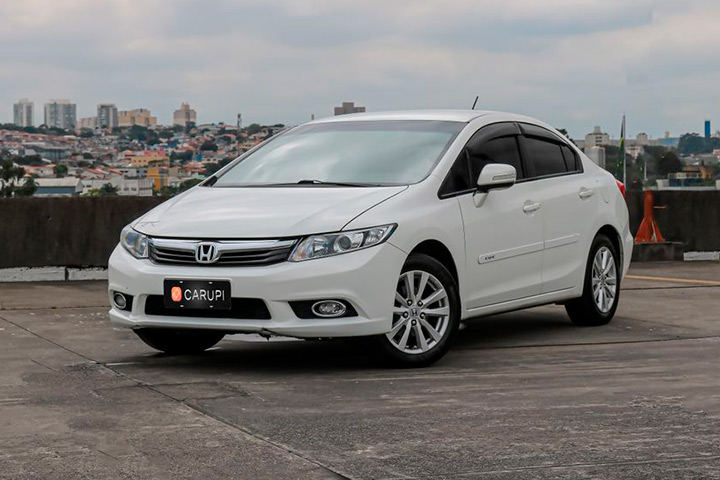 Honda Civic 2014 branco em pátio de prédio alto com skyline da cidade ao fundo