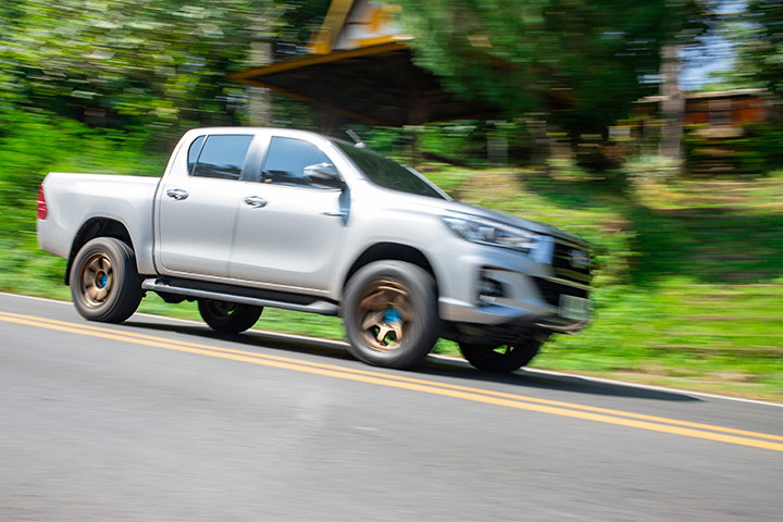 Toyota Hilux prata descendo ladeira com cenário desfocado ao fundo