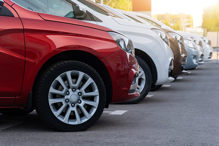 Diversos carros de cores diferentes enfileirados em pátio de estacionamento