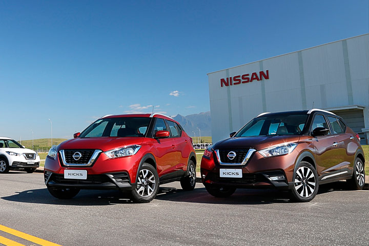 Três modelos de Nissan Kicks (vermelho, marrom e branco) parados em frente à fábrica da Nissan em Resende, no Rio de Janeiro