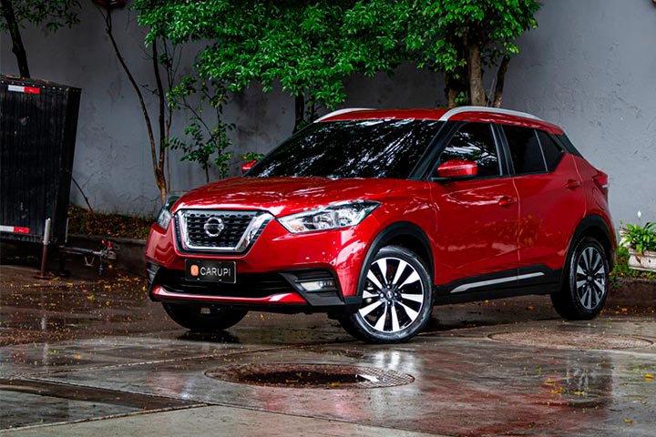 Nissan Kicks vermelho estacionado em pátio de cimento molhado pela chuva