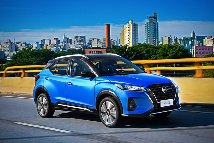 Nissan Kicks azul modelo 2022 trafegando em viaduto de São Paulo com cidade ao fundo
